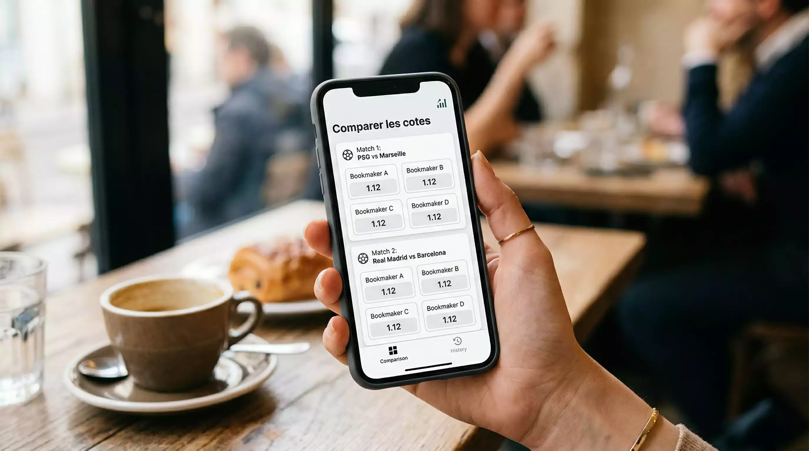 Main tenant un smartphone avec plusieurs applications de paris sportifs ouvertes pour comparer les cotes